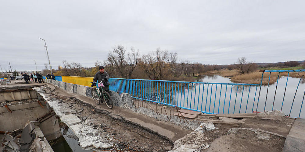 Ein alter Mann schiebt sein Fahrrad auf einem schmalen Streifen der Brücke, die durch den Beschuss russischer Truppen in Kupiansk zerstört wurde, das von den russischen Invasoren befreit wurde, Region Charkiw, Nordosten der Ukraine. Foto: Ukrinfor...