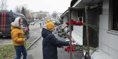 Ein Junge (r) legt eine rote Nelke nieder, nach einem Brand in einem Nachtclub. Nach dem Brand in einem russischen Nachtclub mit mehreren Toten ermitteln die Behörden wegen Fahrlässigkeit mit Todesfolge. Foto: Dmitry Serebryakov/AP/dpa