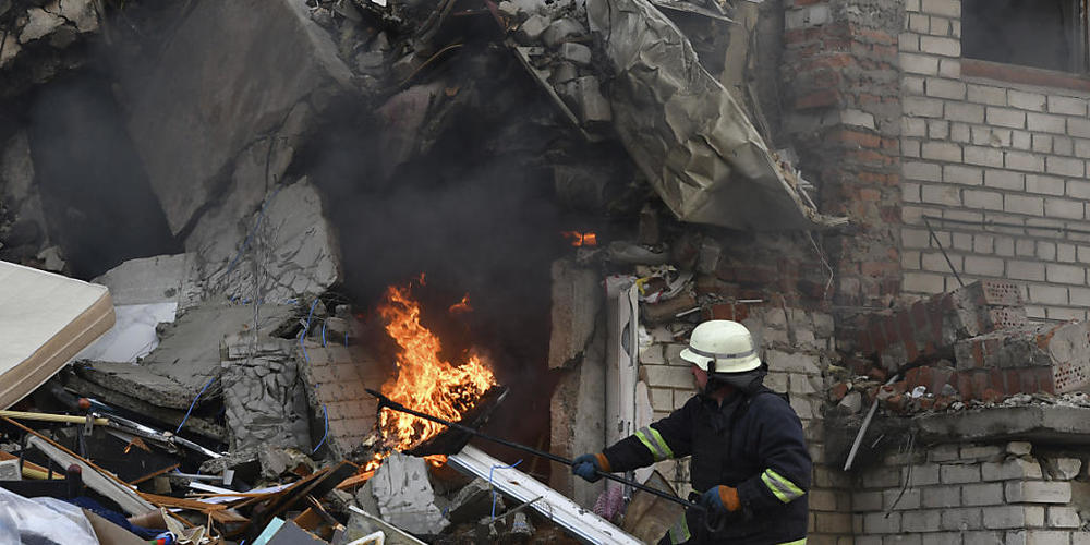 dpatopbilder - Ein Feuerwehrmann löscht einen durch Beschuss ausgelösten Brand in einem zerstörten Wohnhaus. Foto: Andriy Andriyenko/AP/dpa