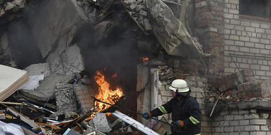 dpatopbilder - Ein Feuerwehrmann löscht einen durch Beschuss ausgelösten Brand in einem zerstörten Wohnhaus. Foto: Andriy Andriyenko/AP/dpa