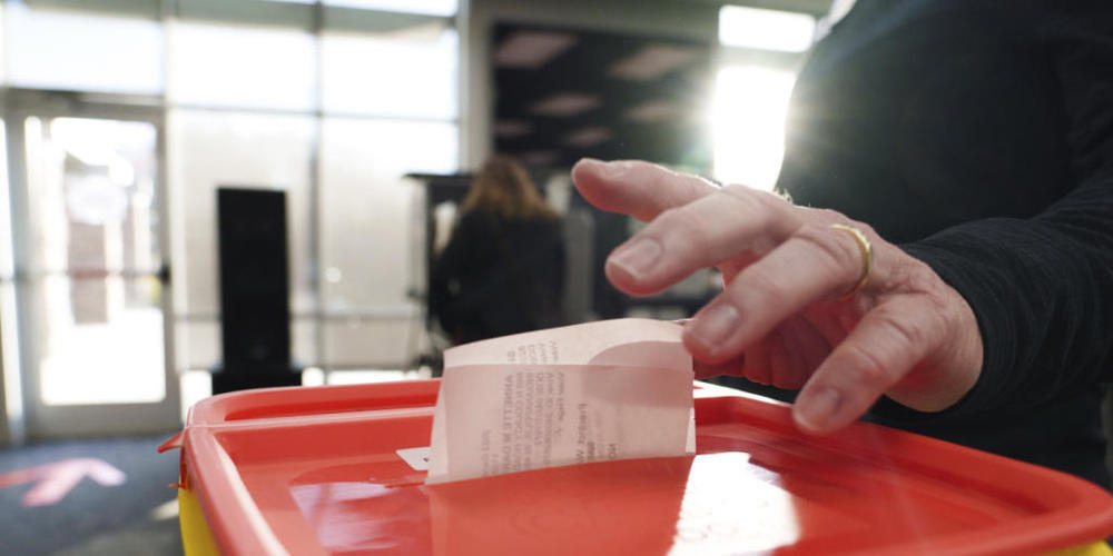 Ein Mitarbeiter eines Wahllokals wirft am Wahltag in Indiana seinen Stimmzettel in einen Eimer. Foto: Mykal Mceldowney/The Indianapolis Star/AP/dpa