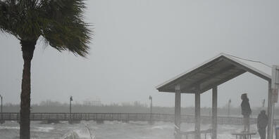Menschen trotzen dem Regen und dem starken Wind, um die Uferpromenade entlang des Jensen Beach Causeway zu besuchen. Foto: Rebecca Blackwell/AP/dpa