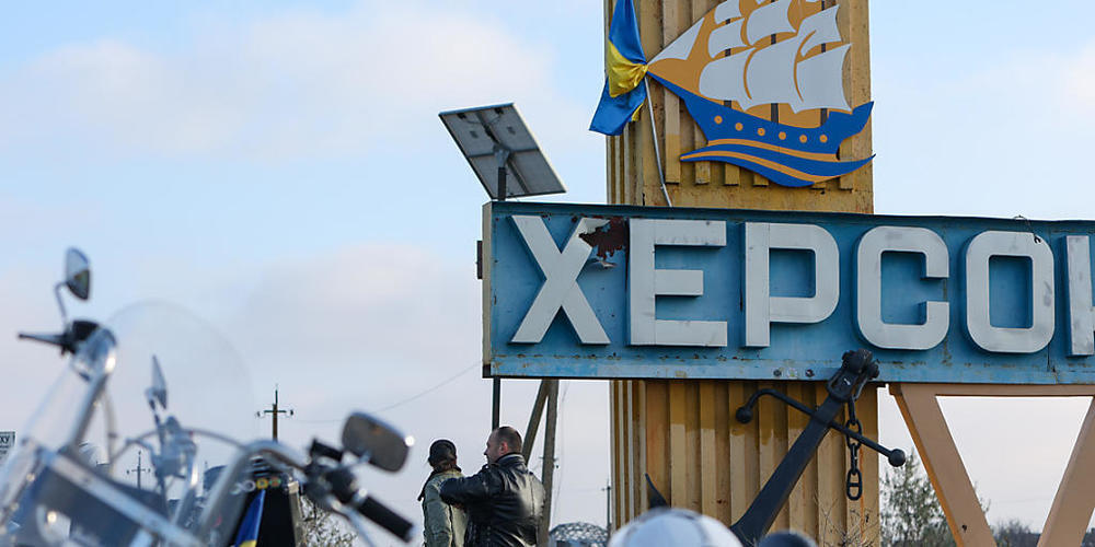 Motorradfahrer stehen vor einem Straßenschild mit der Aufschrift «Cherson». Nach dem russischen Abzug rücken die Ukrainer weiter auf die Gebietshauptstadt Cherson im Süden ihres Landes vor. Foto: Daniel Ceng Shou-Yi/ZUMA Press Wire/dpa
