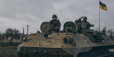 Ukrainische Soldaten zeigen ein Peace-Zeichen, während sie mit einem erbeuteten russischen Schützenpanzer fahren. Foto: Libkos/AP/dpa
