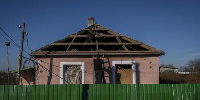 Dorfbewohner reparieren ein Haus in Schewtschenkowe. Foto: Bernat Armangue/AP/dpa