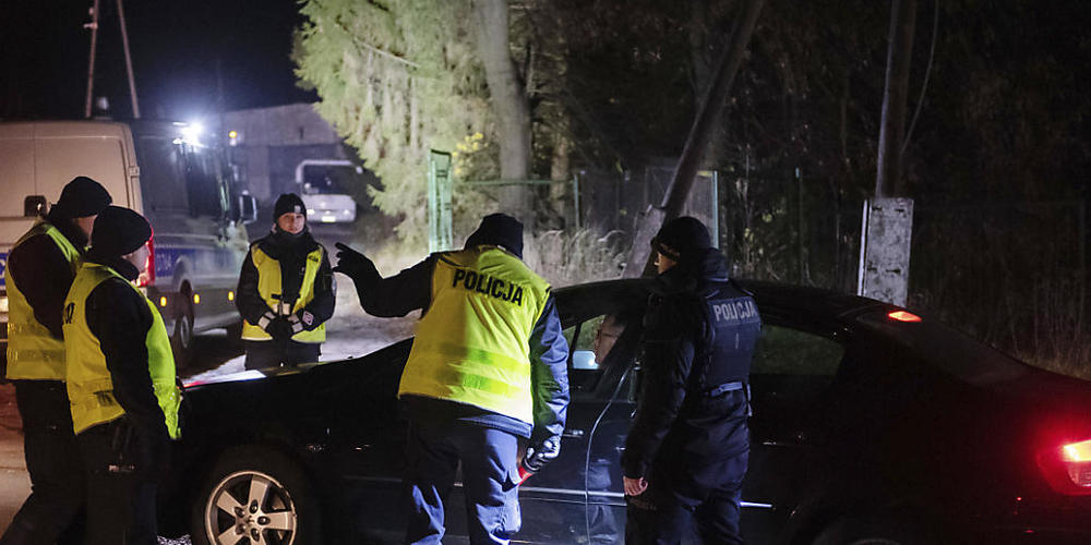 Polizisten versammeln sich nahe dem Einschlagsort einer Rakete russischer Bauart in Przewodow im Südosten Polens. Foto: Str/AP/dpa