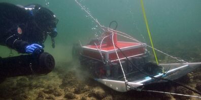 Ein Taucher führt den Georadarschlitten über eine Steinschüttung.