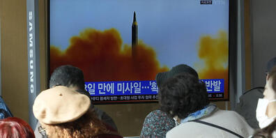 Menschen sitzen nahe eines Monitors auf dem eine Nachrichtensendung mit einem Archivbild über den neusten Raketentest Nordkoreas berichtet. Foto: Ahn Young-Joon/AP/dpa
