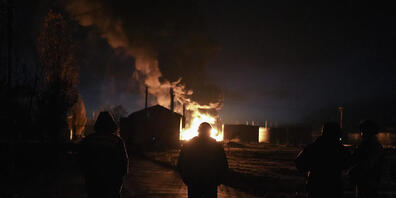 Menschen stehen in Cherson vor einer Rauchwolke während eines Brandes, der laut ukrainischen Angaben durch einen russischen Angriff verursacht wurde. Foto: Roman Hrytsyna/AP/dpa