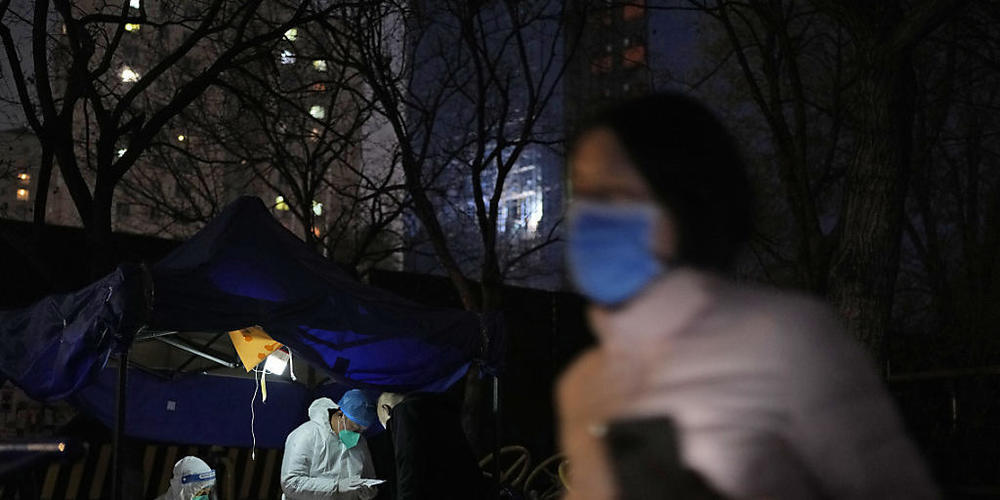 ARCHIV - Eine Anwohnerin geht in Peking an einer Station zur Entnahme von Abstrichproben für Corona-Tests vorbei. Foto: Ng Han Guan/AP/dpa