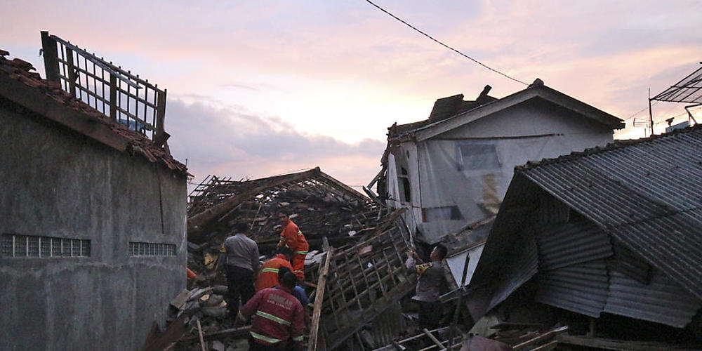 Nach dem Erdbeben laufen die Bergungsarbeiten zwischen den zerstörten Häusern. Foto: Rangga Firmansyah/AP/dpa
