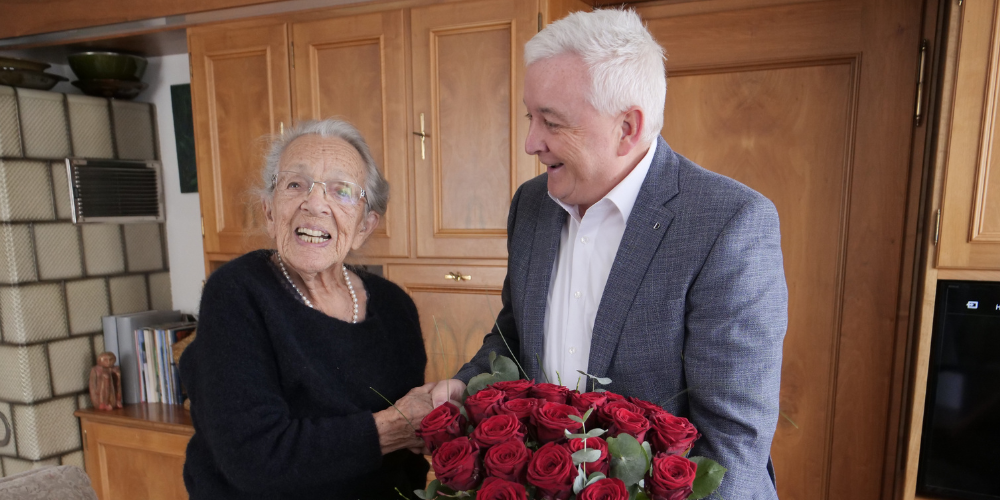 Gemeindepräsident Roland Wälter überreicht der Jubilarin einen Rosenstrauss. 