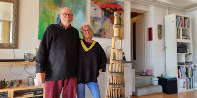 Das Künstlerpaar im Atelier im Haus am Fallenbach mit Bildern von Mia Stauber und der Fibonacci-Pagode von Reinhard Nesper.