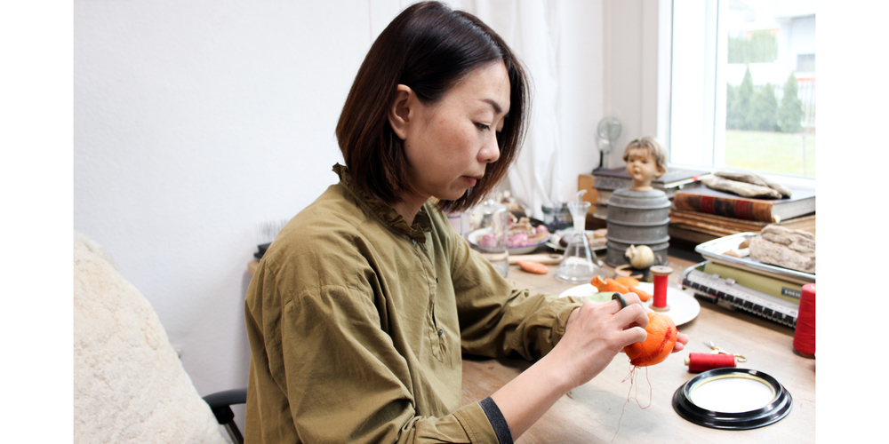 Ying Xu flickt die Haut einer Mandarine in ihrem Atelier in Feuerthalen.