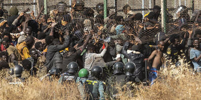 ARCHIV - Migranten auf spanischem Boden, nachdem sie die Zäune zwischen der spanischen Exklave Melilla und Marokko überquert haben. Foto: Javier Bernardo/AP/dpa
