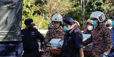 Rettungskräfte befördern gemeinsam eine Trage. Die Anzahl der Verstorbenen im Zusammenhang mit einem Erdrutsch auf einem Campingplatz ist auf 31 angestiegen, nachdem die letzte vermisste Person gefunden wurde. Foto: Amirul Azmi/BERNAMA/dpa