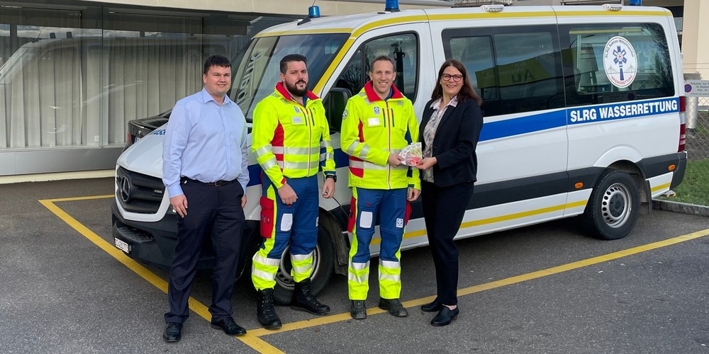 Nicolas Dietsche und Susanne Indermaur (SGKB) mit Kevin Berger (Kommunikationsverantwortlicher) und Jöel Rodi (Präsident SLRG Sektion Mittelrheintal) bei der Spendenübergabe vor dem Einsatzfahrzeug. 
