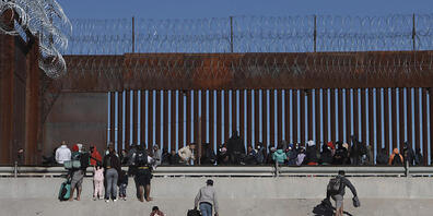 Migranten nähern sich der Grenzmauer zwischen Mexiko und den USA. Foto: Christian Chavez/AP/dpa