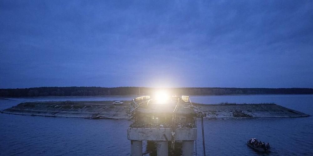 Ein Boot fährt über den Fluss Siverskyi-Donets vor einer zerstörten Brücke. Russland hat mit Drohnen- und Raketenangriffen in der Ukraine erneut schwere Zerstörungen angerichtet. Foto: Evgeniy Maloletka/AP/dpa
