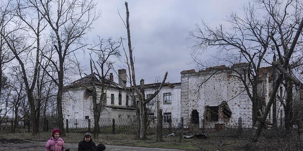 Anwohner gehen an einer Schule vorbei, die nach einer Schlacht zerstört wurde. Foto: Evgeniy Maloletka/AP/dpa