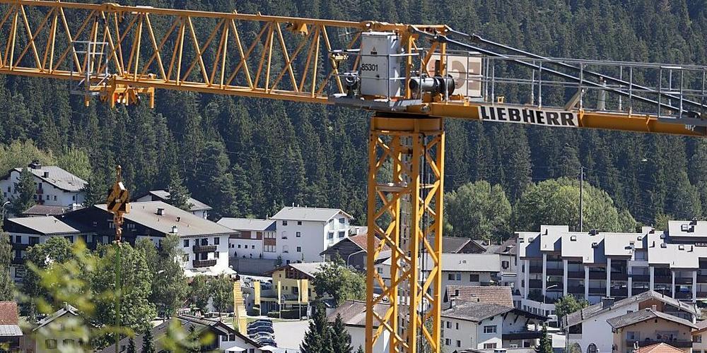 Ein Baukran über der Gemeinde Laax GR. Entgegen früherer Aussagen will die Bündner Regierung die Wohnungsnot in Graubünden nun doch auch auf kantonaler Ebene angehen. (Archivbild)