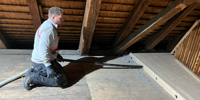 Mit einem langen Rohr bläst der Vorarbeiter Jonas Bertsch die Zellulose in den Hohlraum des neuen Estrichbodens.