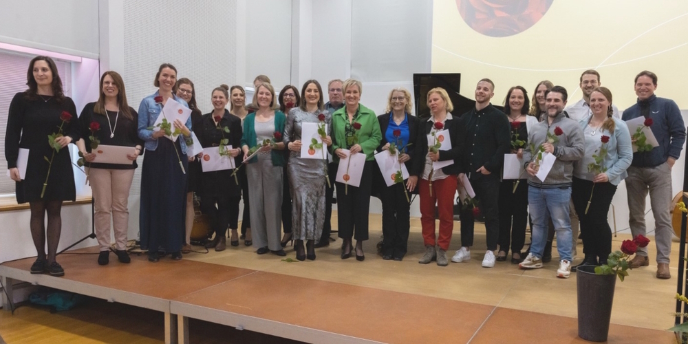 Die 23 frisch gebackenen Heilpädagoginnen und -padägogen mit ihren Diplomen und roter Rose.