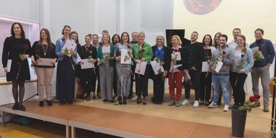 Die 23 frisch gebackenen Heilpädagoginnen und -padägogen mit ihren Diplomen und roter Rose.
