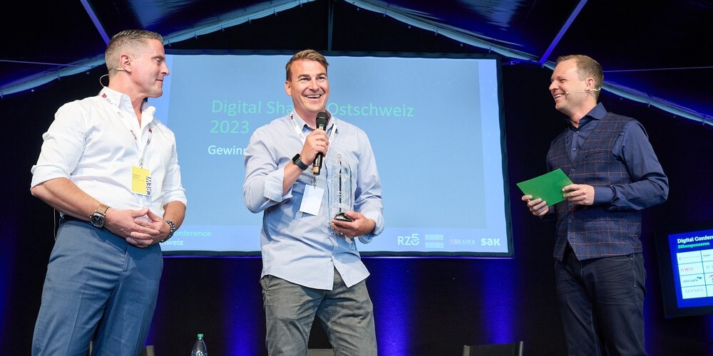 Der gebürtige Schmeatter Roger Spirig durfte von LEADER-Chefredaktor Stephan Ziegler (links) den Pokal in Empfang nehmen. Rechts Conference-Moderater Christoph Lanter. 