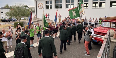 Mehrere Grüninger Vereine stehen mit ihren Fahnen Spalier für den Jodelclub Bärgblueme.