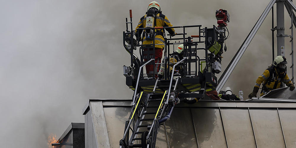Feuerwehrleute bekämpfen den Brand auf dem Dach eines Bürogebäudes.