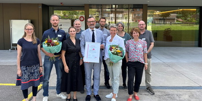 Abbildung 1: Stolzes Team der Berit Klinik PSA Wattwil mit Peder Koch (Mitte, hält Urkunde), CEO und Delegierter des Verwaltungsrats Berit Kliniken; rechts davon Priska Eigenmann, Standortleiterin Berit Klinik Wattwil; links von ihm Pamela Städler, Stellenleiterin Selbsthilfe St. Gallen-Appenzell. Von li.n.re. Andrea Wälti, Kunsttherapeutin; Oskar Spär, Systemischer Therapeut- und Bewegungstherapeut; Rainer Hartmann, Psychologe; Timm Könnecke, Psychologe; Tamara Wittenwiler, Dipl. Pflegefachfrau HF, Isabelle Nessensohn Psychologin; Peter Baumgartner, Stv. Leiter PSA