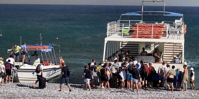 Auf Rhodos retten sich Touristen auf ein Schiff.