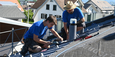 Symbolbild: Ein Spenglerlehrling montiert unter der Aufsicht seines Lehrmeisters Aluminiumziegel.