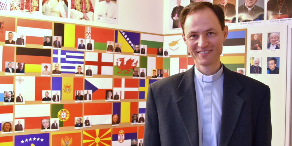 Der heutige Generalsekretär des CCEE, Martin Michalíček, vor der Wand mit den Vertretern der europäischen Bischofskonferenzen.