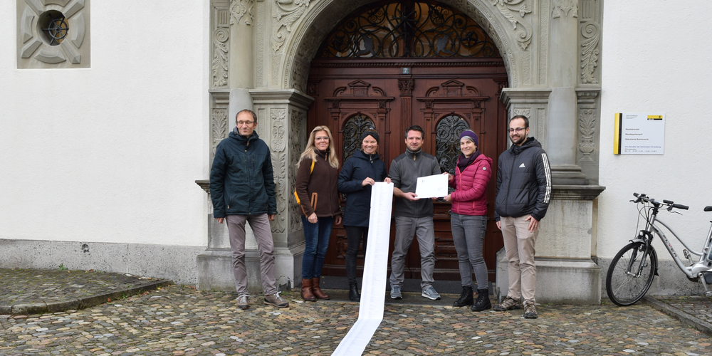 Vor dem Regierungsgebäude rollt der LSH ein 6.5 Meter langes Blatt mit allen 1388 Unterschriften aus, während die Petition einem Vertreter des Kantons übergeben wird.