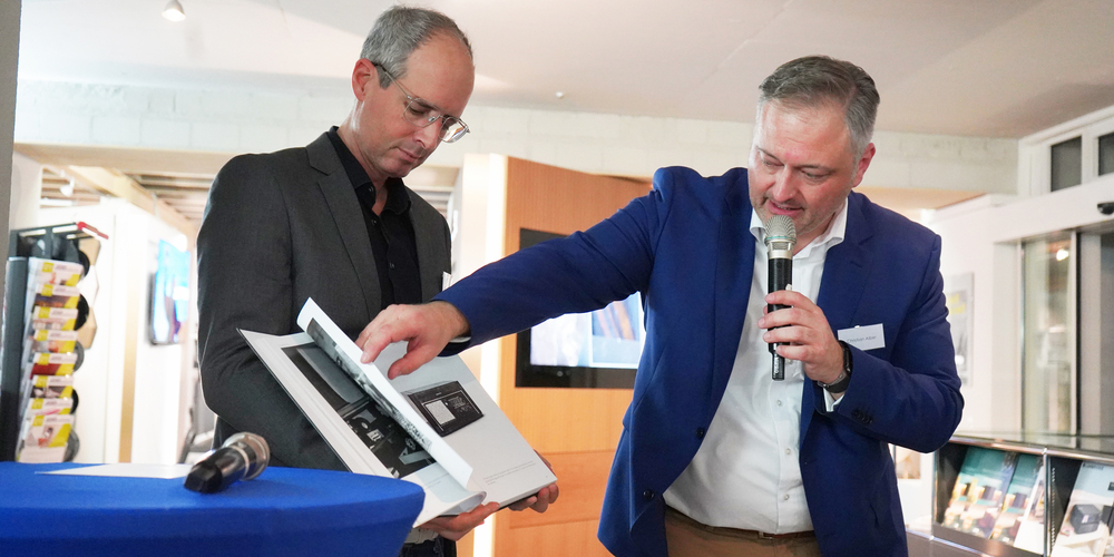 Thomas Gründler (l.) erhielt von LOEWE-COO Christian Alber einen Sonderdruck über die 100-jährige Geschichte der Marke.