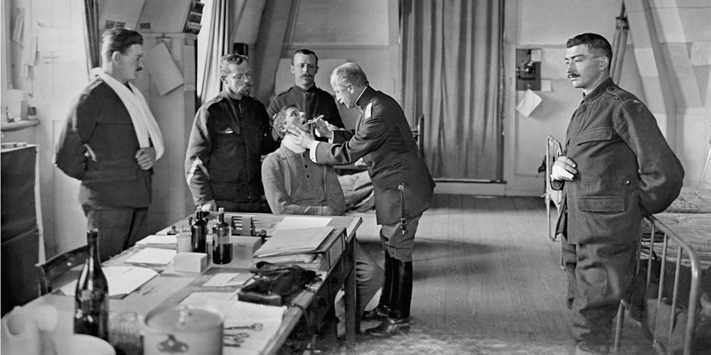 Ein Truppenarzt untersucht während des Ersten Weltkrieges Schweizer Armeeangehörige in einem Krankenzimmer. Die eigentliche Bewährungsprobe der Truppensanität kam mit der Epidemie der Spanischen Grippe.