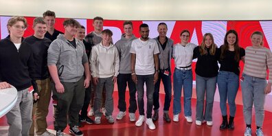 Die Lernenden zusammen mit Marathonläufer Tadesse Abraham (6. von rechts) im Sportpanorama Studio