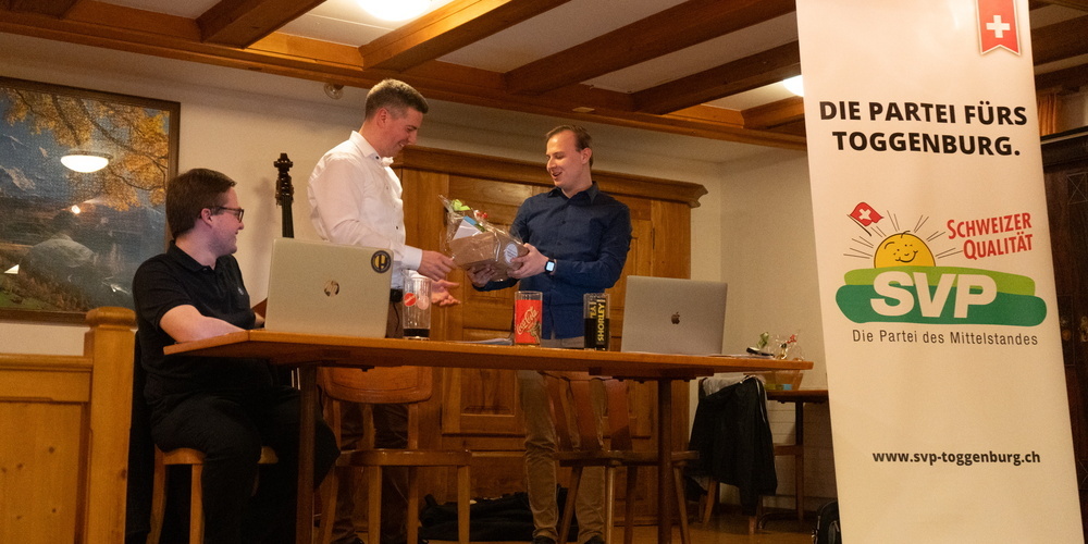 Der neue Präsident Lukas Huber (ganz rechts im Bild) übergibt dem abtretenden Präsident Thomas Bösch (in der Mitte im Bild) ein Präsent.