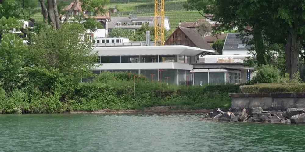Die Villa von Roger Federer ist fast fertig, aber am Seeufer klafft noch eine Lücke. Da wo das Bootshaus geplant ist, stecken orange Visiere.