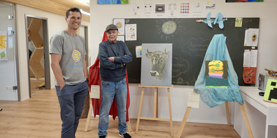 Dr. Thomas Kochanek (l.) Leiter des Immersive Learning Space im Gespräch mit dem Kunstmaler Jürg Hirrlinger vor einem seiner bekannten Kuh-Bilder.