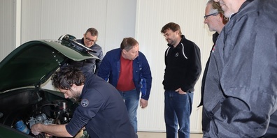 Die Kursteilnehmer besammeln sich rund um um einen dunkelgrünen VW Karmann Ghia, Jahrgang 1968 und Kursleiter Marvin Pfister erklärt die technischen Details.