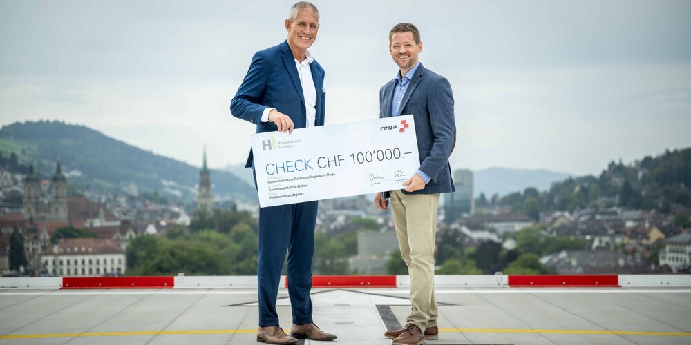 Symbolische Scheckübergabe am Kantonsspital St.Gallen: Stefan Lichtensteiger (links), CEO Kantonsspital St.Gallen, nimmt von Philipp Simmen (rechts), Leiter Helikopter Einsatz Rega, auf dem neuen Helikopterlandeplatz auf dem Dach von Haus 07 den symbolischen Scheck entgegen.