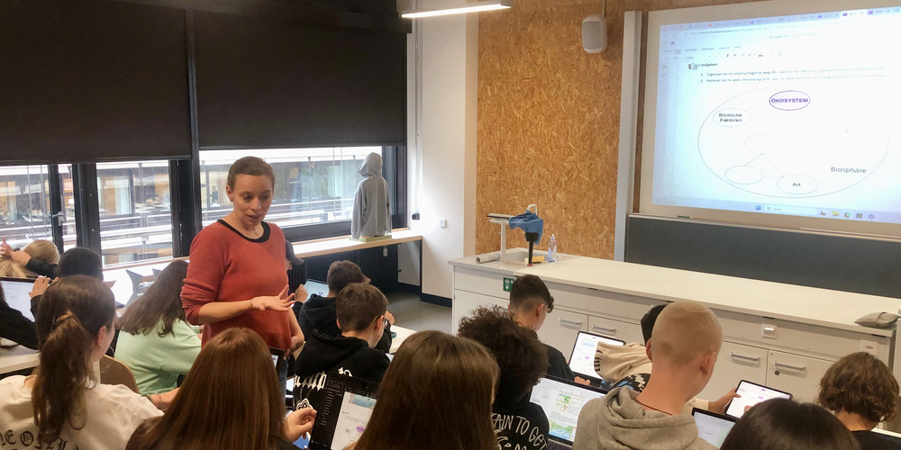 Biologielehrerin Jelena Löwenstein inmitten einer Klasse der Kantonsschule Zürich Nord. Im Hintergrund sieht man gut die Sperrholzwände, die den provisorischen Charakter der Einbauten auf dem Campus Irchel unterstreichen.