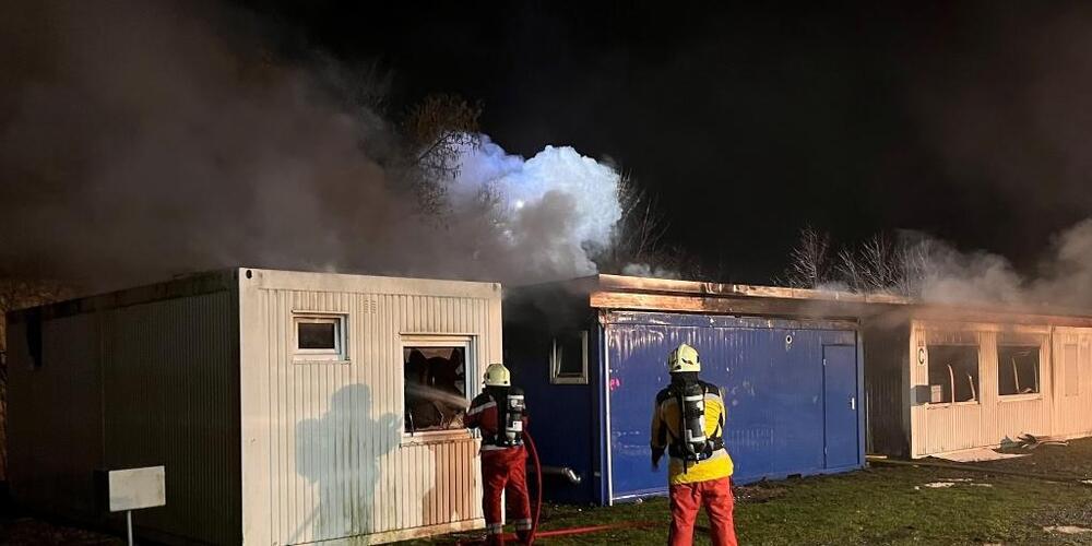 Feuerwehrleute löschen den Brand in einer Containersiedlung für Asylsuchende in Buchs.