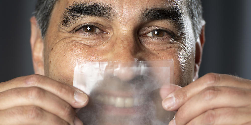 Hello Mask - So heisst die erste vollständig transparente Operationsmaske, die kurz vor der industriellen Herstellung steht. Projektchef Thierry Pelet zeigt mit einem Muster vor dem Gesicht, dass das Gegenüber sein Lächeln erkennen kann.