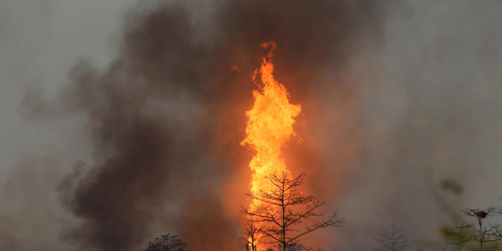 Flammen lodern über einem Ölfeld, nachdem unkontrolliert Gas aus einem Bohrloch geströmt ist und sich entzündet hat. Foto: Str./XinHua/dpa
