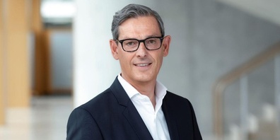 Porträt von Beat Schwab im Anzug vor einer Betonwand.