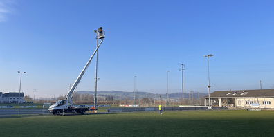 Mitarbeitende der Gemeinde Schübelbach montieren die neuen LED-Leuchten auf dem Sportplatz Rietly in Buttikon.